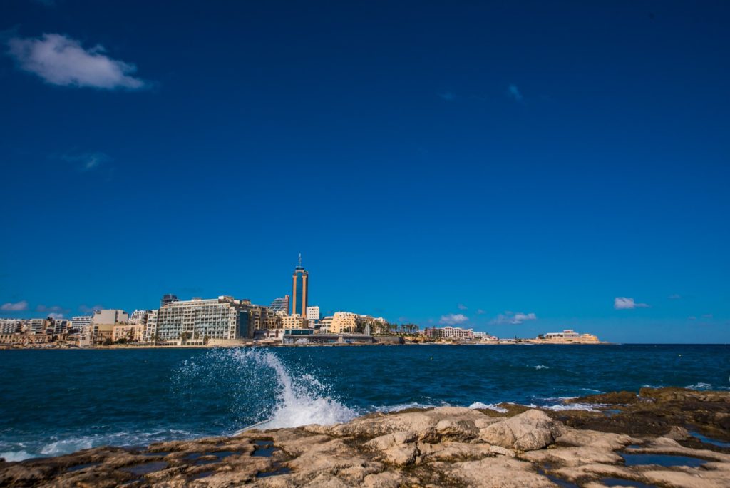 maltese seaside with buildings and the Portomaso Tower in the distance 